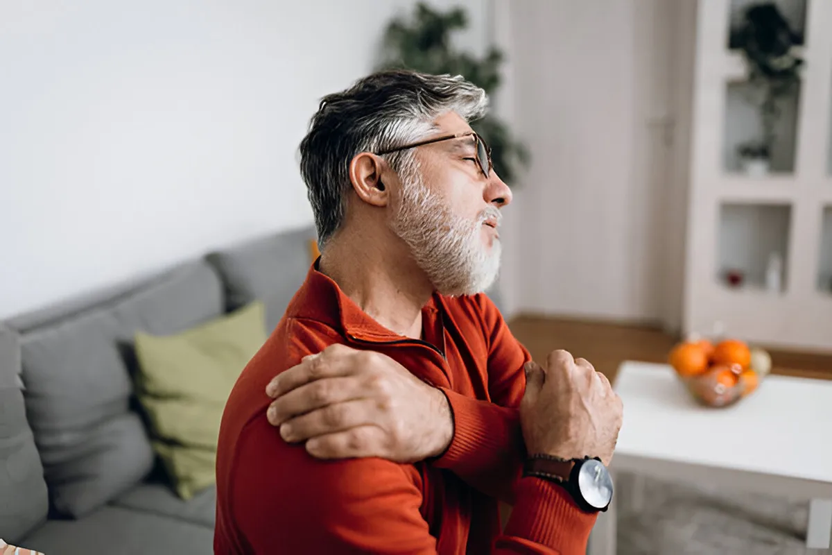 man holding shoulder in intense pain, expressing discomfort man holding shoulder in intense pain, expressing discomfort