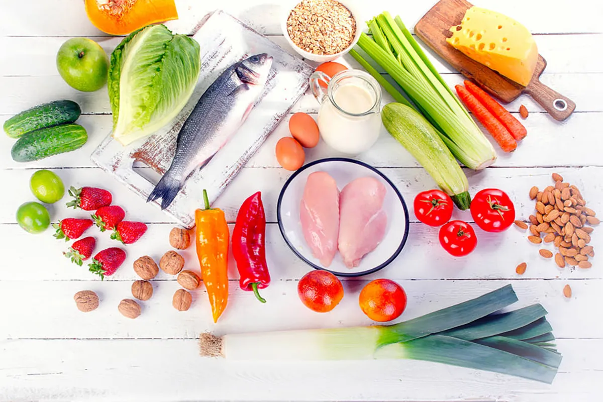 various healthy foods including fruits, vegetables, fish, meat, chicken, dry fruits, and cheese for a balanced diet