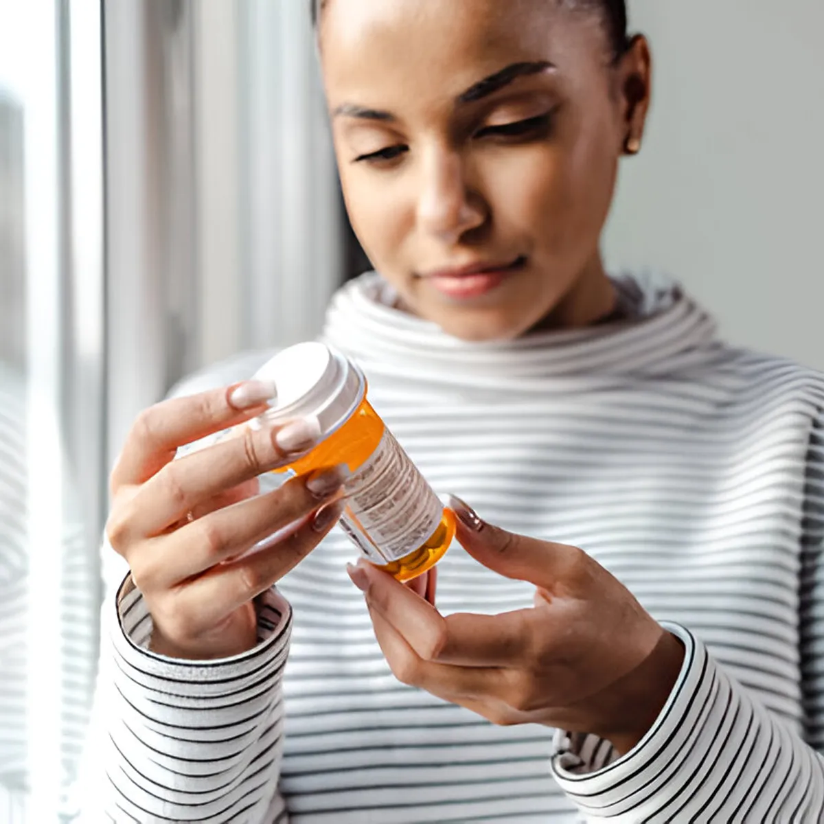 woman reading adderall medicine bottle details woman reading adderall medicine bottle details